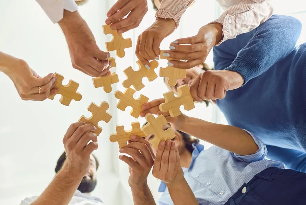 Several hands fitting puzzle pieces together, representing different goals brought to the same starting point