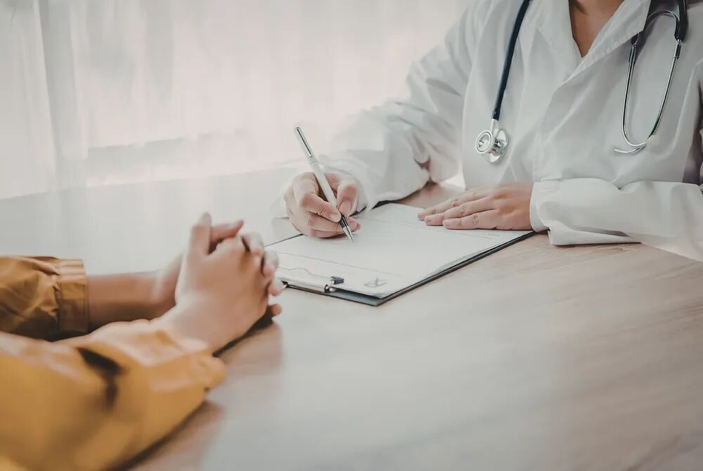 A practitioner making notes across a table during an initial consultation