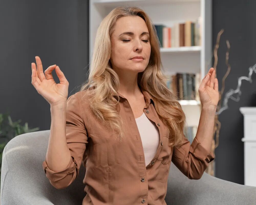A person sitting quietly with eyes closed, taking a moment to settle before a conversation